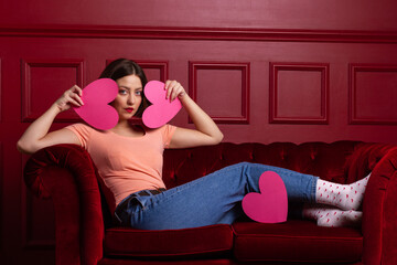 Obraz premium Women on couch holding heart shapes in front of her face