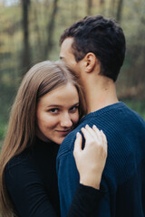 Hugging couple in a forest, girlfriend looking in the camera