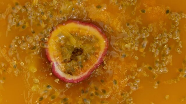 Fresh sliced passion fruit falling into juice, super slow motion filmed on high speed cinematic camera at 1000 fps.