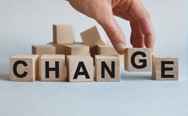 CHANGE inscription on the texture of wooden cubes. A business man holds a cube in his hand. An inscription on a financial, business or economic theme.