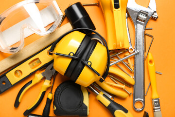 Hearing protectors with builder's tools on color background