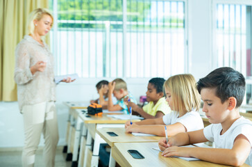 Fototapeta premium School children writing test, smart young people studying at primary school