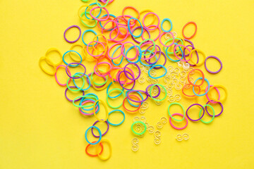 Heap of colorful rubber bands on yellow background