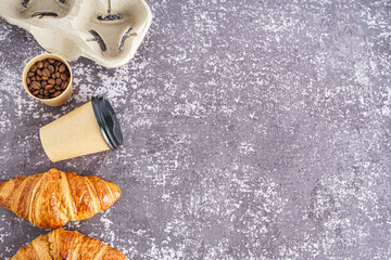 Paper cup, coffee beans and croissants on grunge background