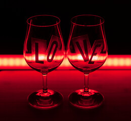 two wine glasses on a background illuminated with red light. Love is written on the glasses. Valentine's Day Love and wine