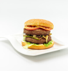 A large burger with a double cutlet, grilled vegetables and sauce. Isolate on a white background, ready-made menu