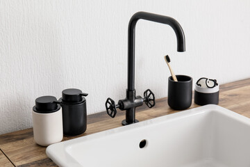 Sink with bath accessories on table near light wall
