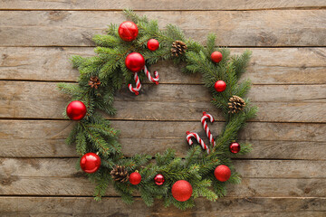 Fototapeta na wymiar Christmas wreath made of fir branches and decorations on wooden background