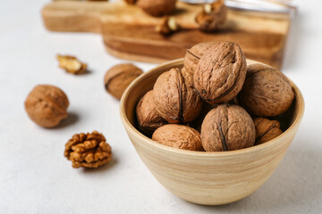 Bowl of fresh walnuts on light background, closeup