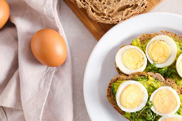 Plate of tasty toasts with boiled egg on light table, closeup