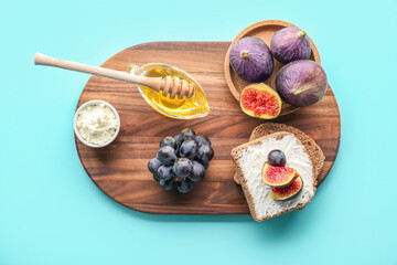 Wooden board of tasty bruschettas with cream cheese, fruits and honey on color background