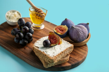 Wooden board of tasty bruschettas with cream cheese and fruits on color background, closeup