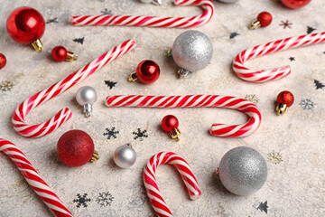 Composition with sweet candy canes and beautiful Christmas balls on light background