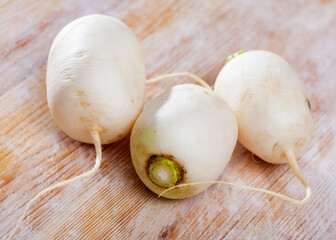 Closeup of whole organic white radishes on wooden surface. Healthy vegetarian ingredient..