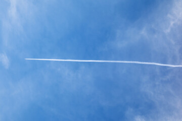 White contrails of plane in blue sky