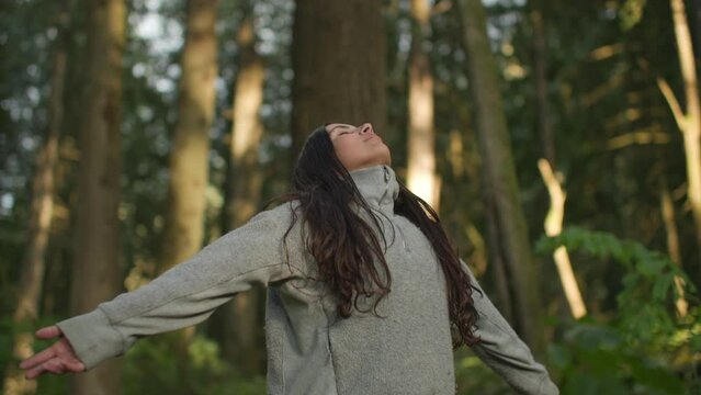 Young attractive female taking deep breath in lush green forest