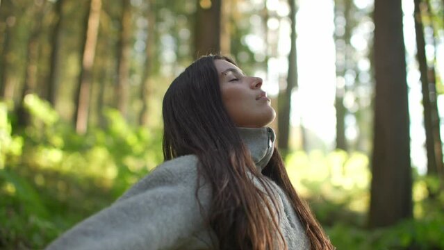 Close up of young attractive female taking deep breath in lush green forest