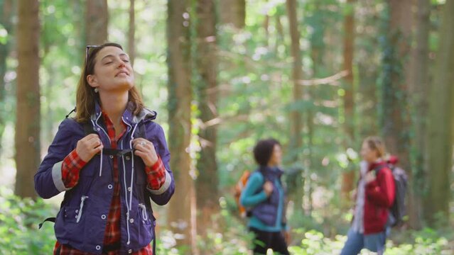 Woman taking deep breath and closing eyes enjoying peace as group of female friends on holiday hike through woods - shot in slow motion