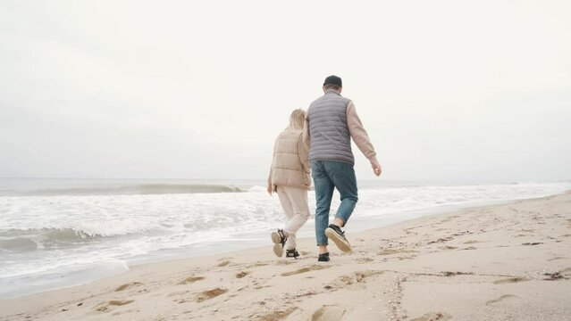 Family couple walking hand in hand on the autumn beach along the ocean