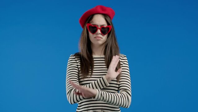 Uninterested woman disapproving with NO hand sign gesture. Denying, rejecting, disagree. Portrait of young lady on blue background, timeout concept.