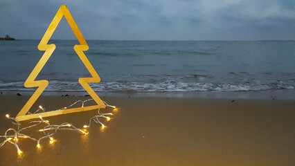 the outline of a Christmas tree on the beach against the background of the sea