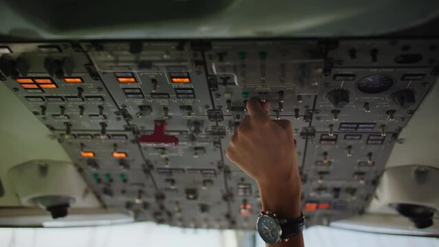 Pilot touching controls in airplane cockpit, control center