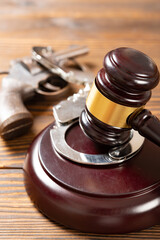 angle view gavel and gun and handcuffs at vertical composition