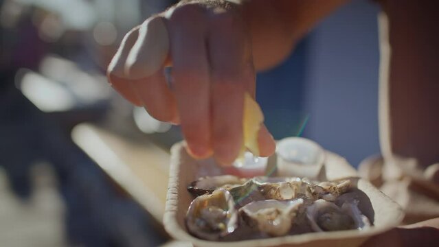 Close up of lemon being squeezed onto oysters