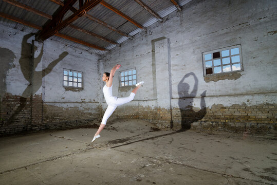 Ballerina in white jumping and dancing in a dusty abandoned building	