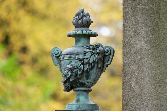 antique funeral urn at a historic cemetery against blurred autumn colors