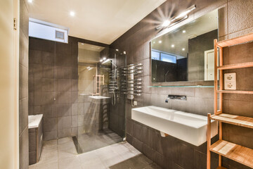 Glass partition between shower tap and wall hung toilet in modern restroom at home