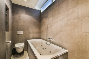 Bathtub with glass shower placed in corner near sink and mirror in small light bathroom
