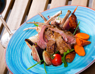 Plate of roasted mutton ribs served with grilled vegetables and fresh figs