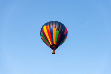 Fototapeta na wymiar A colorful hot air balloon high in the blue sky.