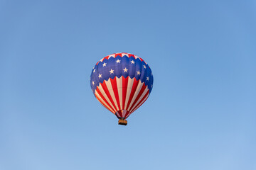 A stars and stripe hot air balloon flying high in the blue sky.