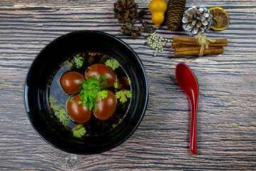 The Stewed Eggs Brown sprinkle coriander in black bowl put on wooden table and copy space