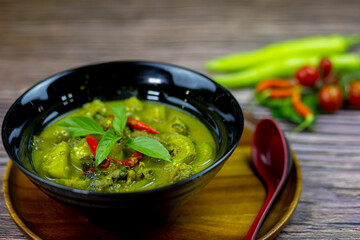 Thai food green curry or Kang Keaw Wan in a black bowl put on a wooden plate and ready to serve is dinner today.
