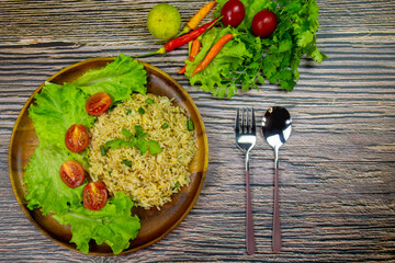 The healthy menu Fried Rice Thai Chinese food with vegetables have lettuce and tomatos sprinkle on top coriander served on a wooden table for breakfast.