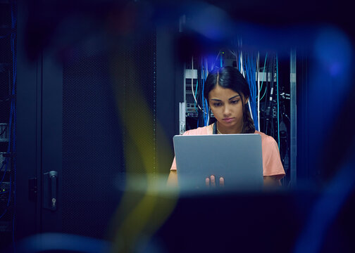 Female technician using laptop in server room