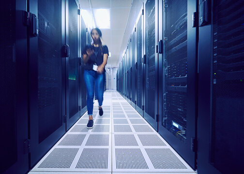 Female technician walking in server room, blurred in motion