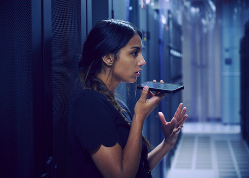 Female technician using smart phone in server room