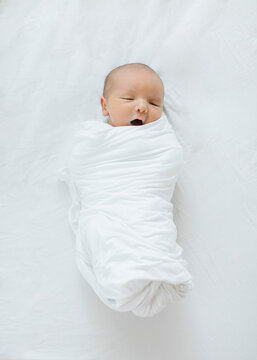 Overhead view of newborn baby boy (0-1 months) swaddled in blanket