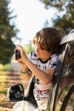Boy (8-9) taking picture from car
