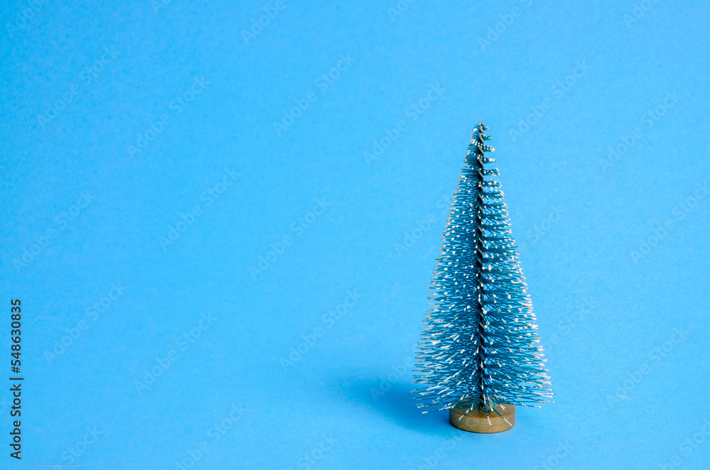 Wall mural Blue artificial Christmas tree with on blue background with copy space. Christmas concept. Christmas card.