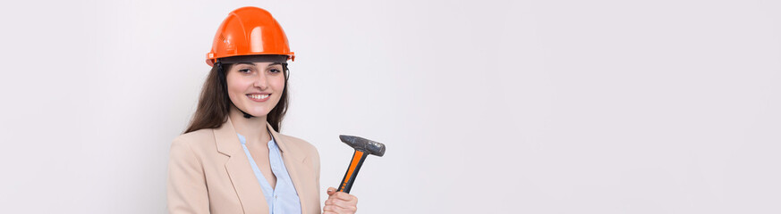 Girl engineer in an orange construction helmet with a hammer on a white background.