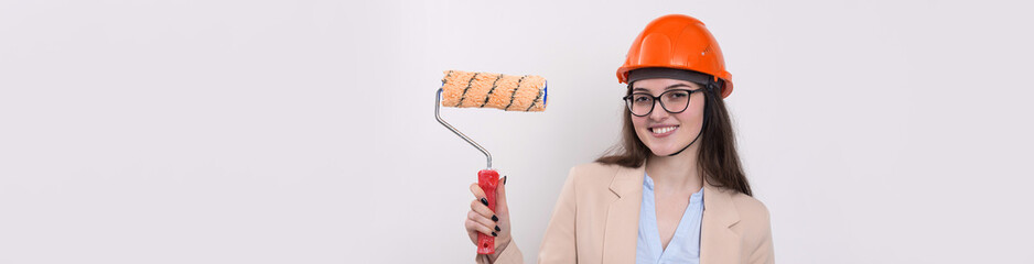Girl engineer in an orange construction helmet with plastering painting tools in her hands on a white background.