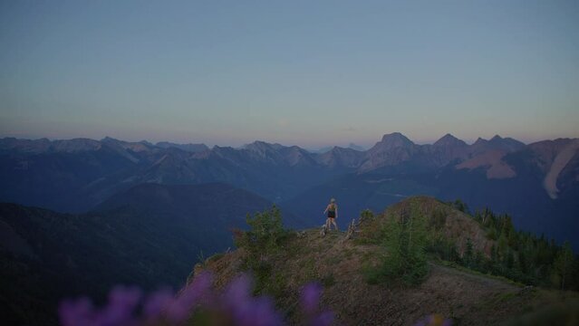 Young adventurous woman walks out mountain viewpoint to view mountain range