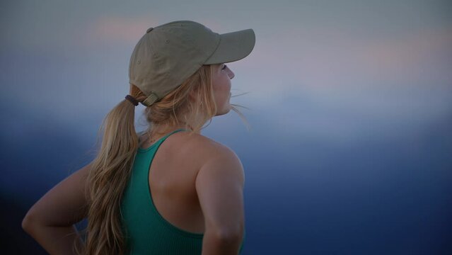 Close up of happy emotional female on mountain top looking at beautiful mountain peaks