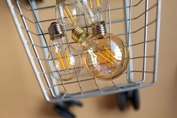 Fototapeta na wymiar Purchase of electricity.lot of electric lamps in a shopping cart.Consumption and payment for energy consumption.Light bulbs in a supermarket trolley on a beige background