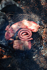 grill with meat, chorizos and roasted vegetables in argentinian patagonia, prepared in a wild environment